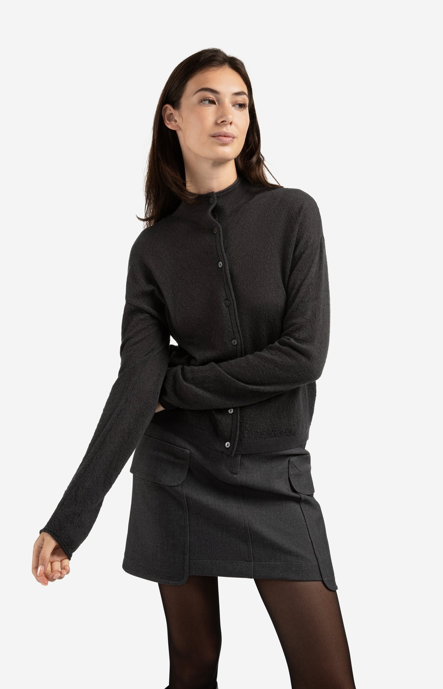 Gebreide cardigan met opstaande kraag en knoopsluiting in een diepe antracietkleur. De zachte stof en minimalistische afwerking geven dit tijdloze ontwerp een moderne, verfijnde uitstraling. Perfect voor gelaagde looks of als subtiel statement piece – YAYA